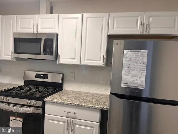 a kitchen with granite countertop a sink cabinets and stainless steel appliances