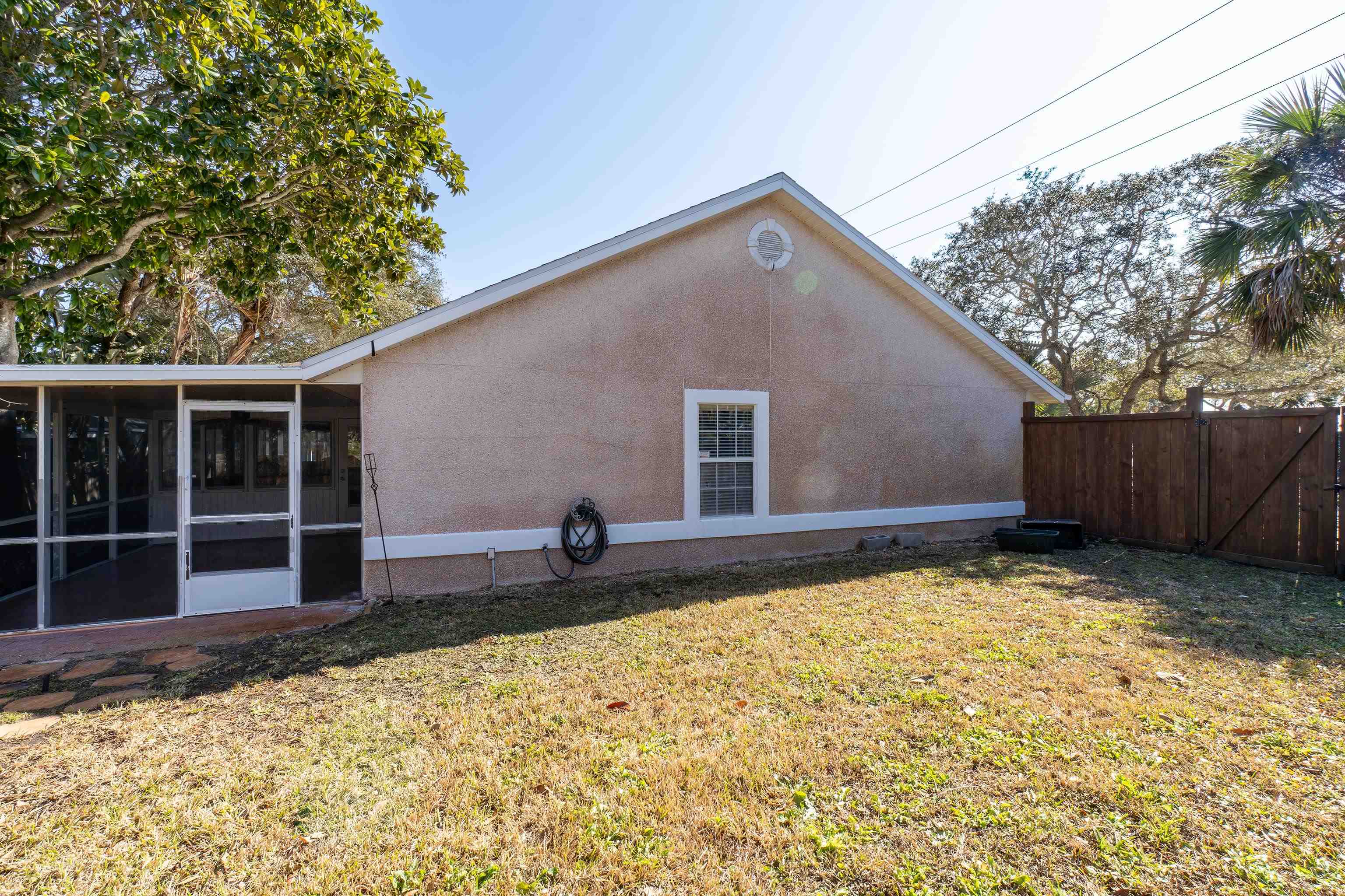 240 Micklers Road St. Augustine, FL 32080 - Photo 23 of 74 Back of house featuring stucco siding, a sunroom, and a gate