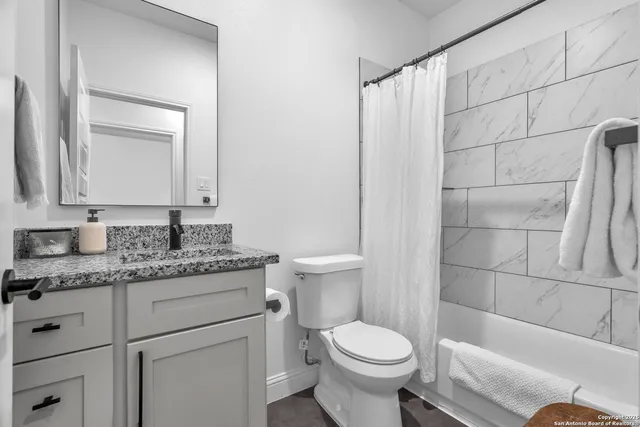 a bathroom with a granite countertop toilet sink and mirror