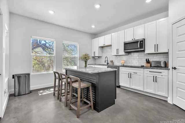 a kitchen with stainless steel appliances granite countertop a stove a sink a microwave a refrigerator a dining table and chairs