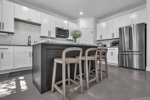 a kitchen with stainless steel appliances a table chairs microwave and refrigerator