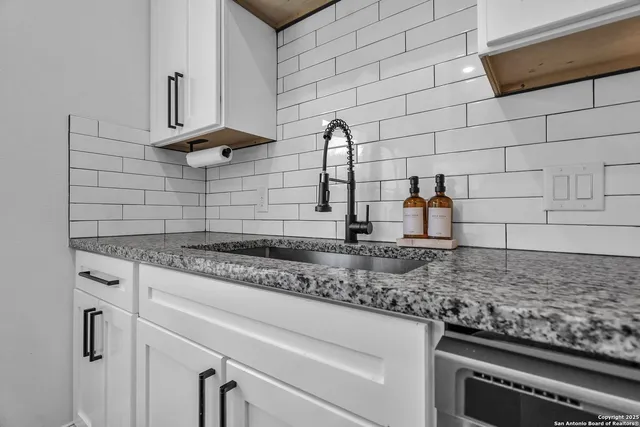 a kitchen with granite countertop white cabinets and a stainless steel appliances