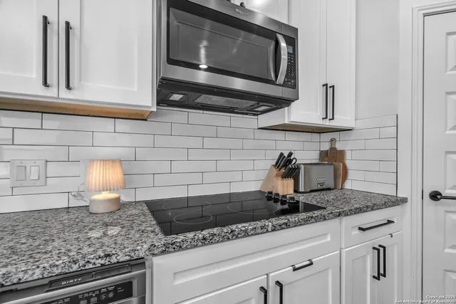 a kitchen with granite countertop white cabinets stainless steel appliances and a sink
