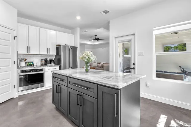 a kitchen with kitchen island granite countertop a sink stove and refrigerator