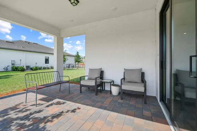 a view of swimming pool with outdoor seating and trees in the background