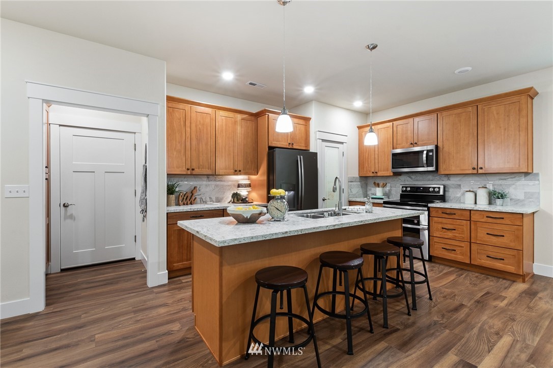 17839 Southeast 128th Street Renton, WA 98059 - Photo 7 of 35 a kitchen with stainless steel appliances granite countertop wooden cabinets a refrigerator a stove a microwave and island with wooden floor