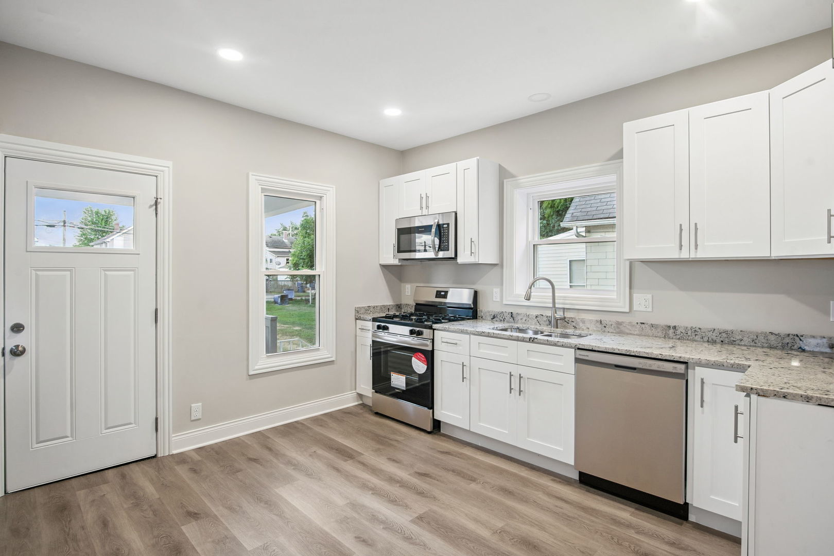1424 Clark Street DeKalb, IL 60115 - Photo 14 of 23 a kitchen with stainless steel appliances granite countertop a stove top oven a sink dishwasher and a refrigerator with wooden floor
