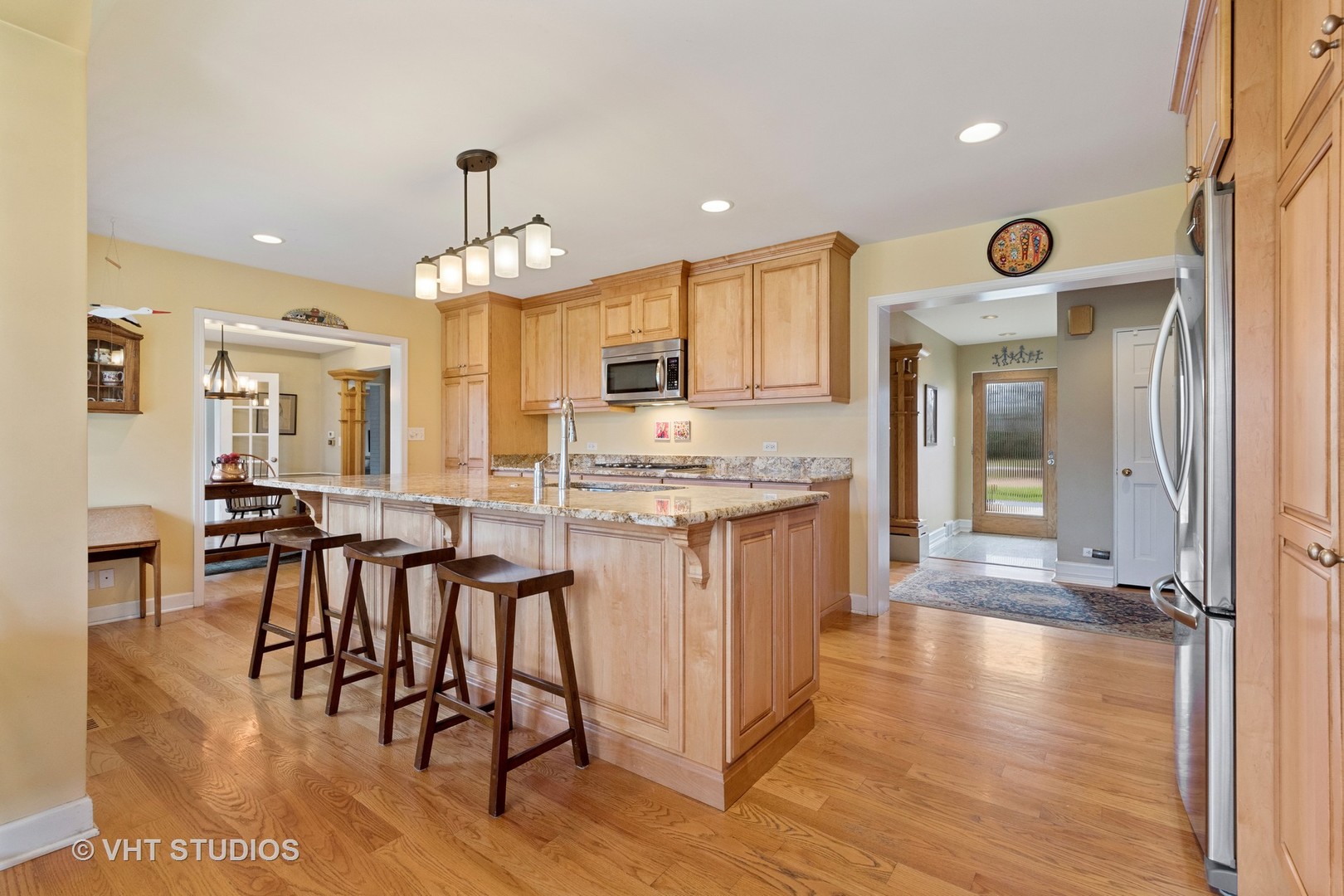 375 Maple Row Northfield, IL 60093 - Photo 6 of 38 a kitchen with stainless steel appliances granite countertop a stove top oven a sink a dining table and chairs with wooden floor