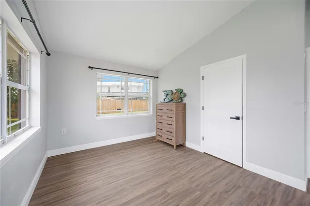 an empty room with wooden floor cabinet and windows