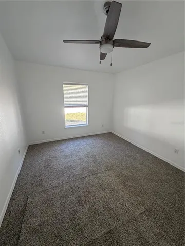 an empty room with a ceiling fan and window