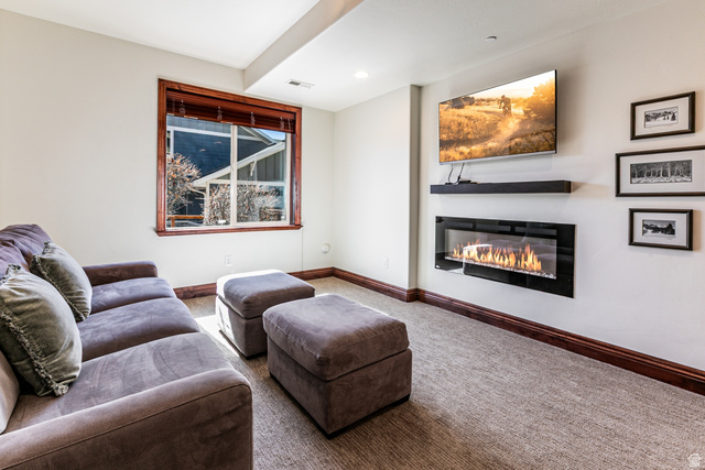 5326 North Oldgate Road Heber City, UT 84032 - Photo 20 of 32 Living area featuring a contemporary wall-mounted linear fireplace, neutral carpeting, and a window with wood trim