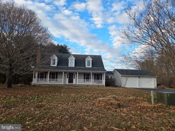 a view of a white house with a large tree next to a yard