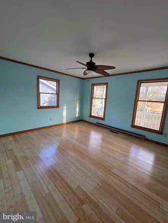 a view of an empty room with window and wooden floor