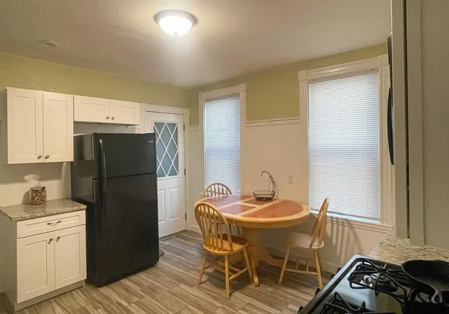a kitchen with a refrigerator a stove a sink and a dining table with wooden cabinet