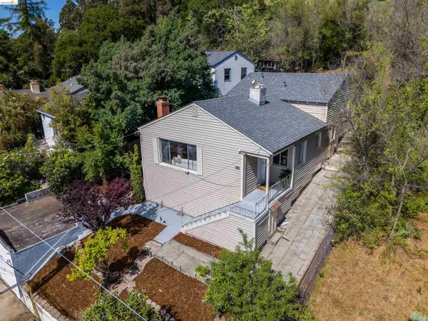 a aerial view of a house with yard and trees in the background