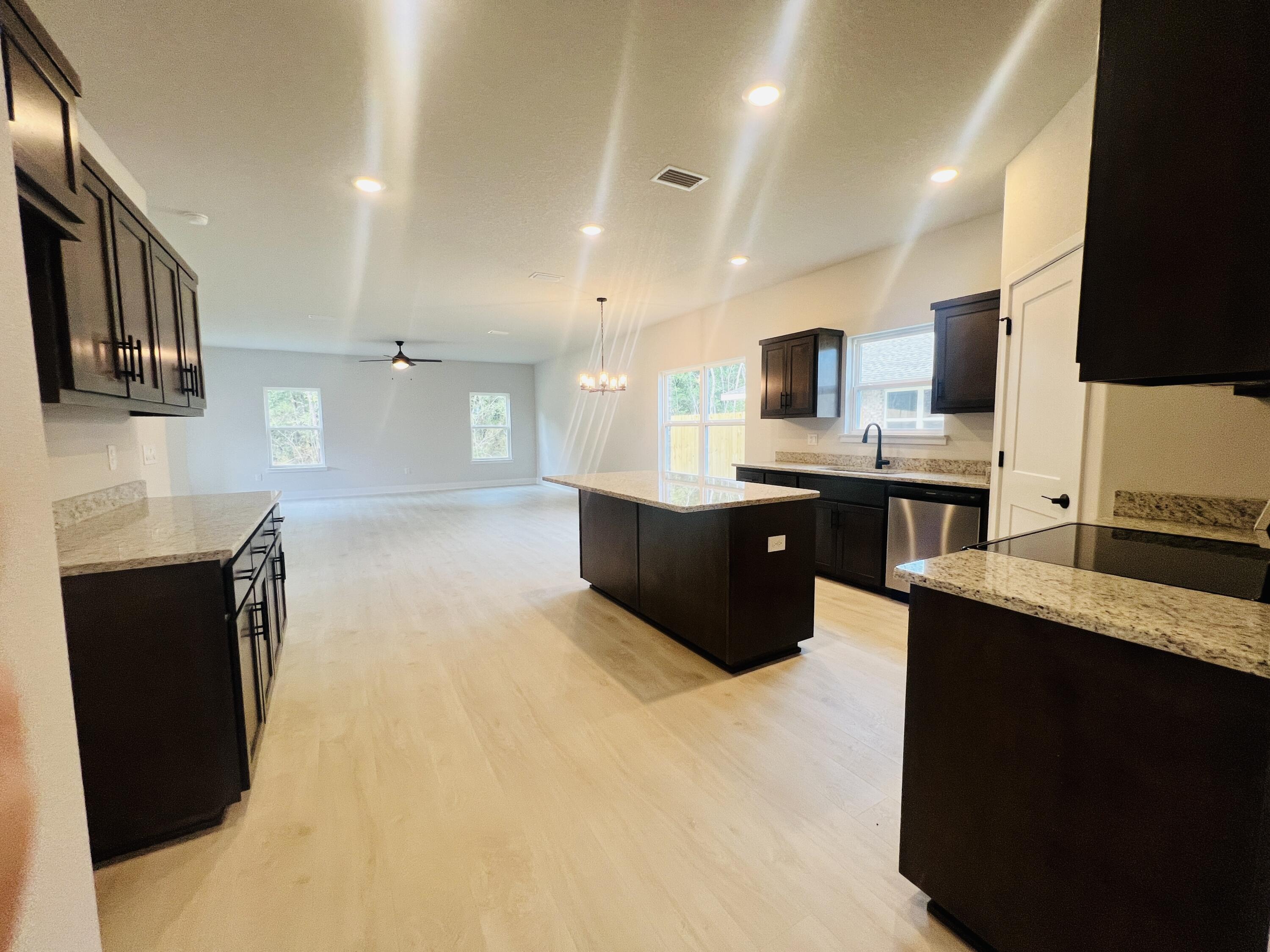 5291 Hidden Pines Circle Milton, FL 32583 - Photo 7 of 21 a large kitchen with stainless steel appliances kitchen island granite countertop a sink and cabinets