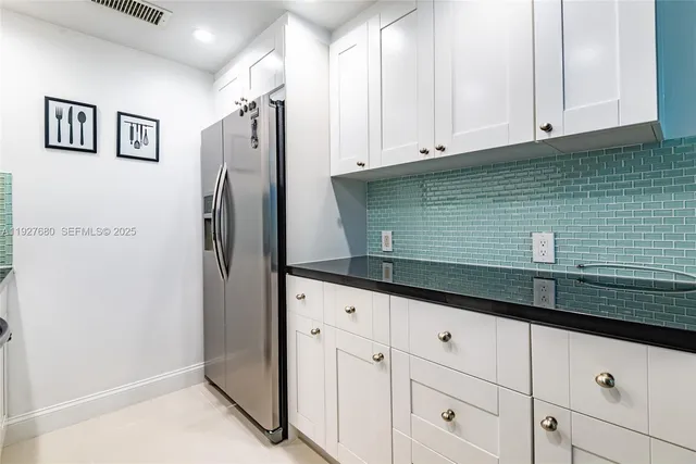 a kitchen with granite countertop a refrigerator and cabinets