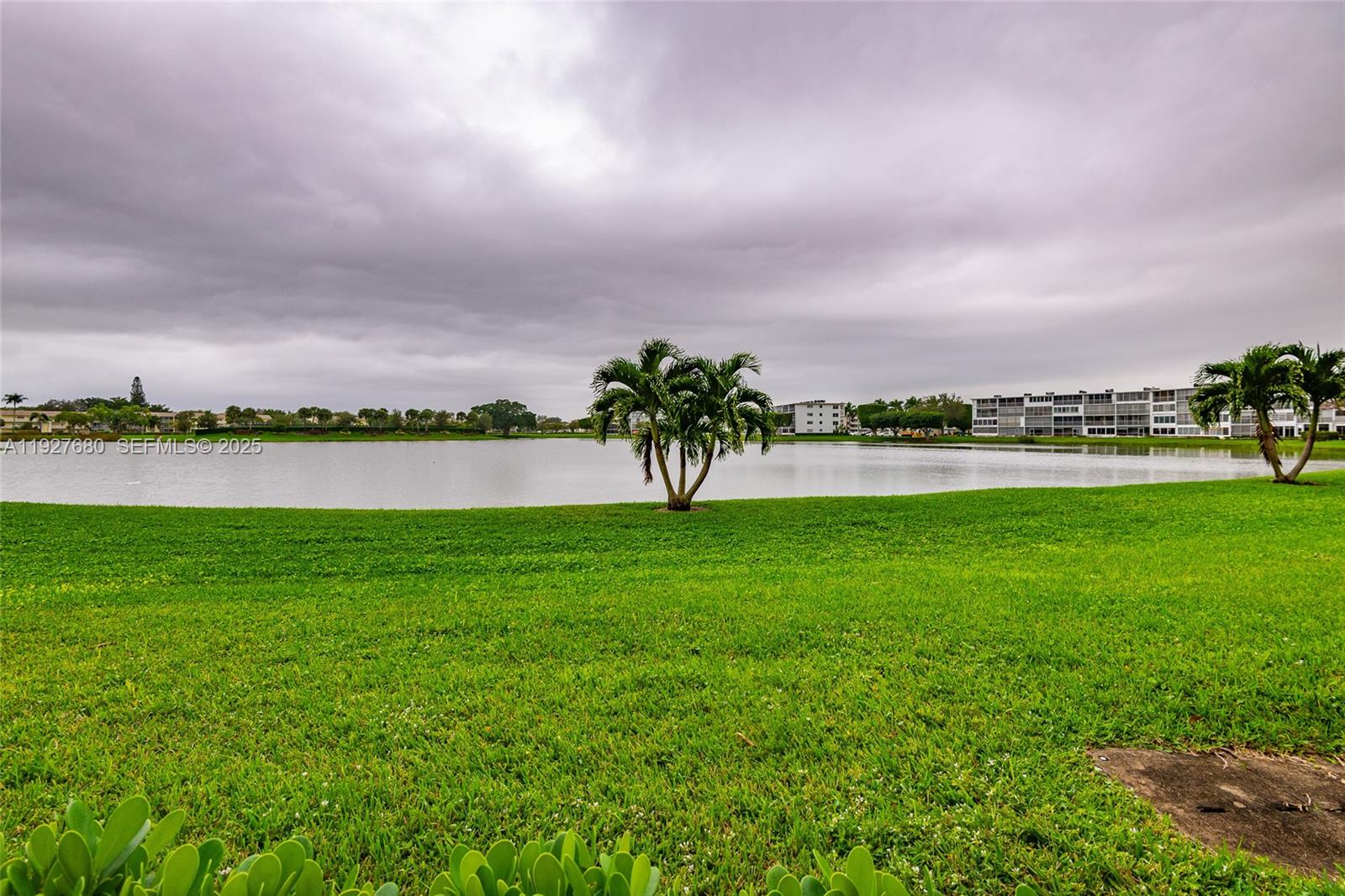 1061 Exeter, Unit 1061D Boca Raton, FL 33434 - Photo 25 of 32 a view of a lake with a big yard and large trees