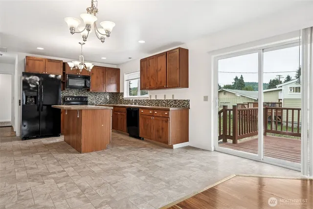 a kitchen with stainless steel appliances granite countertop a stove top oven a sink dishwasher a dining table and chairs with wooden floor