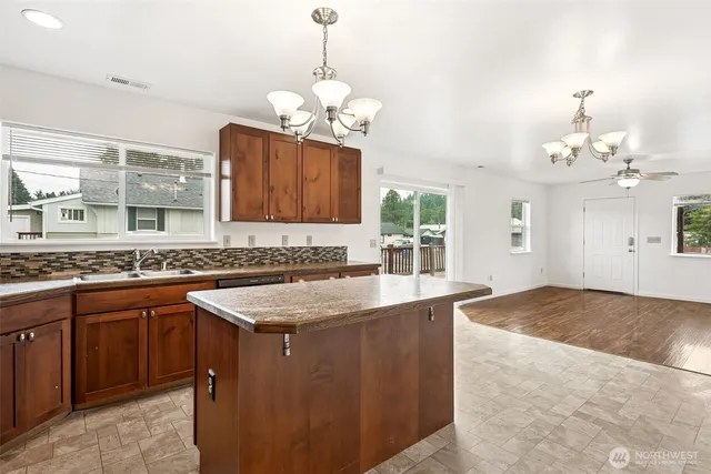 a kitchen with kitchen island granite countertop a sink a counter top space cabinets and stainless steel appliances
