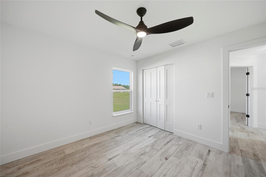 8846 Southwest Liverpool Road Arcadia, FL 34269 - Photo 16 of 49 an empty room with wooden floor ceiling fan and windows