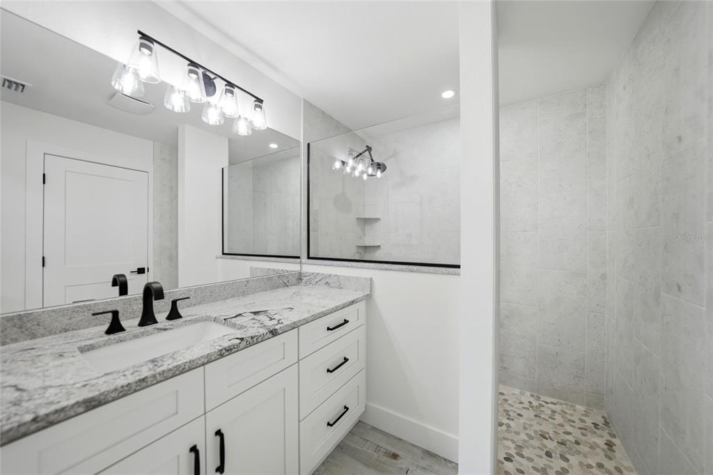 8846 Southwest Liverpool Road Arcadia, FL 34269 - Photo 28 of 49 a bathroom with a granite countertop sink a mirror and a shower