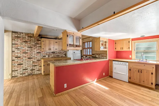 a view of a kitchen with wooden floor and a window