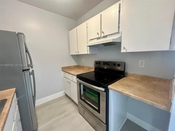 a kitchen with granite countertop white cabinets and a stove