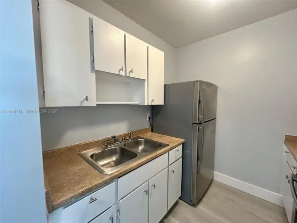 a kitchen with a sink a refrigerator and cabinets
