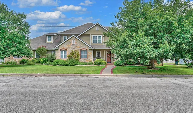 a view of house with a big yard and large trees