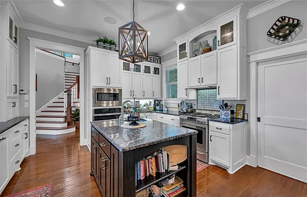 a kitchen with granite countertop a stove a sink a refrigerator and wooden floor