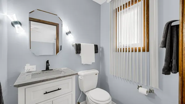 a bathroom with a toilet a sink a mirror a window and vanity