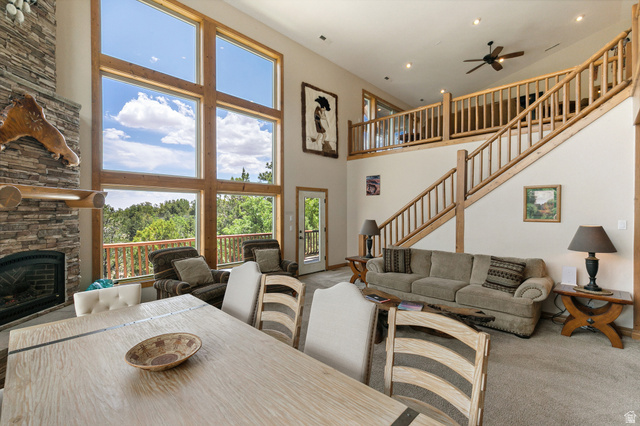 755 South Zion Ridge Drive Orderville, UT 84758 - Photo 41 of 84 Carpeted dining room featuring a ceiling fan, a stone fireplace, and a high ceiling