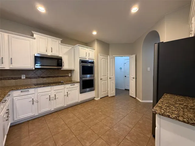 a kitchen with granite countertop a stove and a refrigerator in it