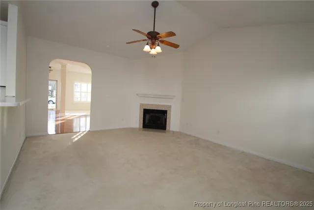 a view of a livingroom with a fireplace a ceiling fan and window