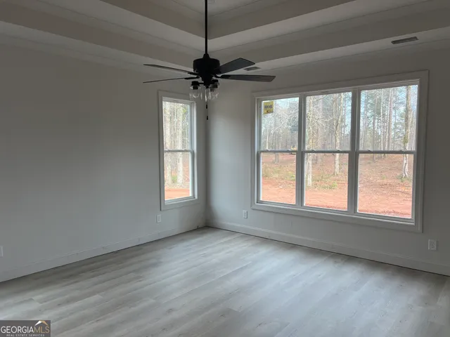 a view of an empty room with a window and wooden floor