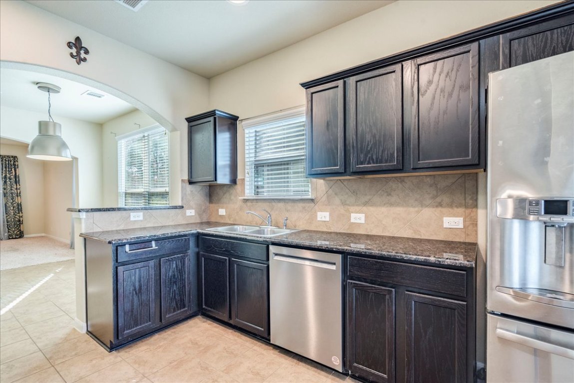 512 Lookout Tree Lane Round Rock, TX 78664 - Photo 11 of 29 Kitchen with stainless steel appliances, backsplash, a peninsula, pendant lighting, and dark stone countertops