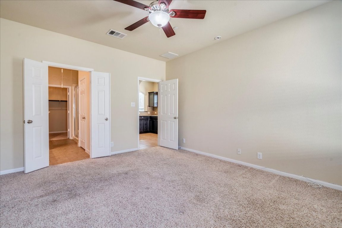 512 Lookout Tree Lane Round Rock, TX 78664 - Photo 13 of 29 Unfurnished bedroom featuring light carpet, ceiling fan, and connected bathroom