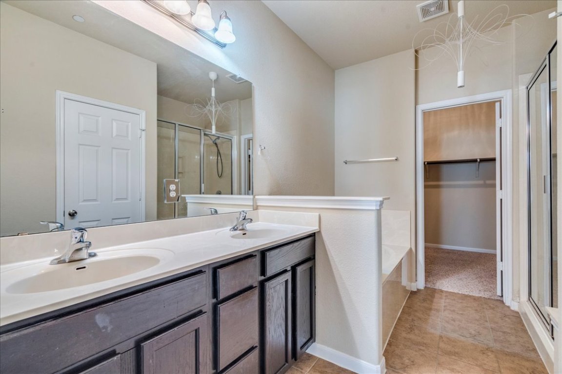 512 Lookout Tree Lane Round Rock, TX 78664 - Photo 14 of 29 Bathroom featuring a stall shower, a walk in closet, double vanity, and a garden tub