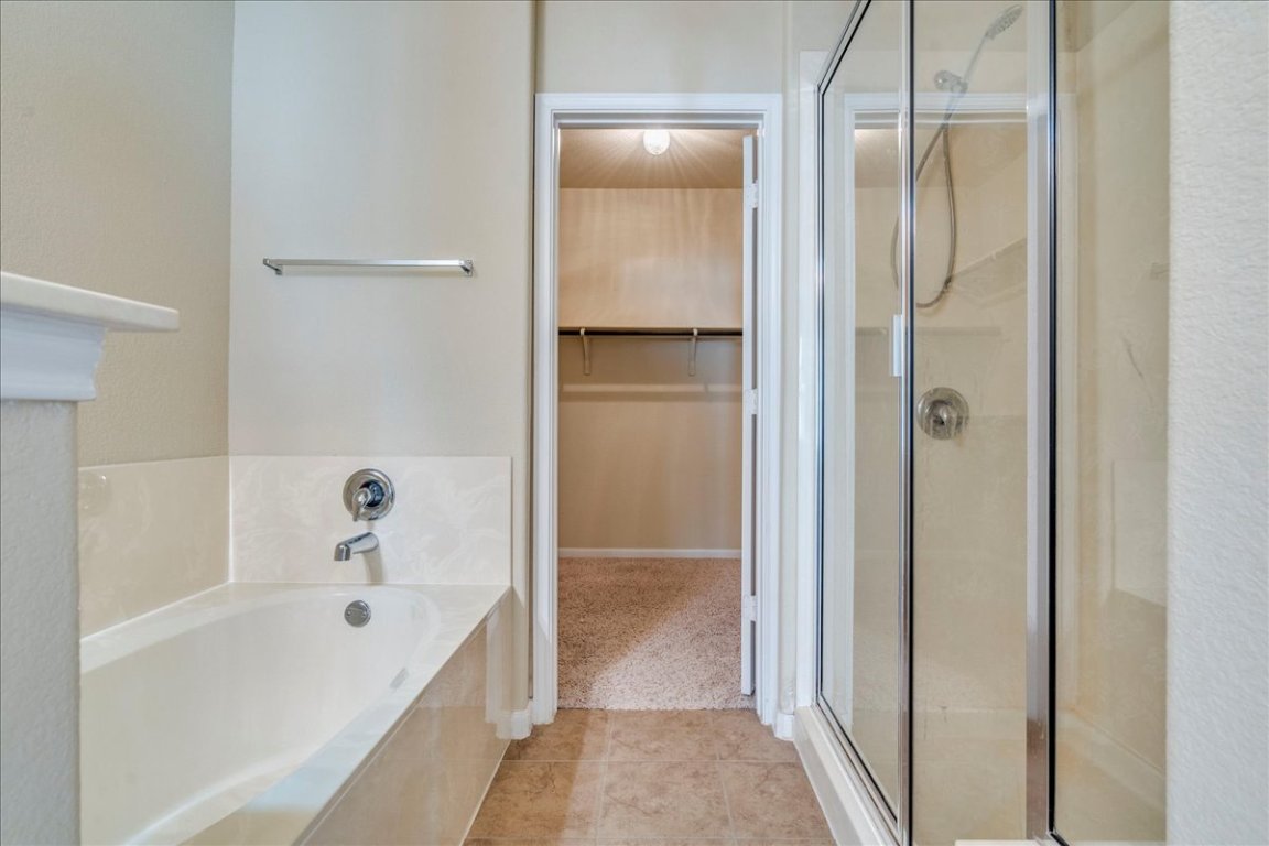 512 Lookout Tree Lane Round Rock, TX 78664 - Photo 15 of 29 Bathroom featuring a walk in closet, a stall shower, and a garden tub