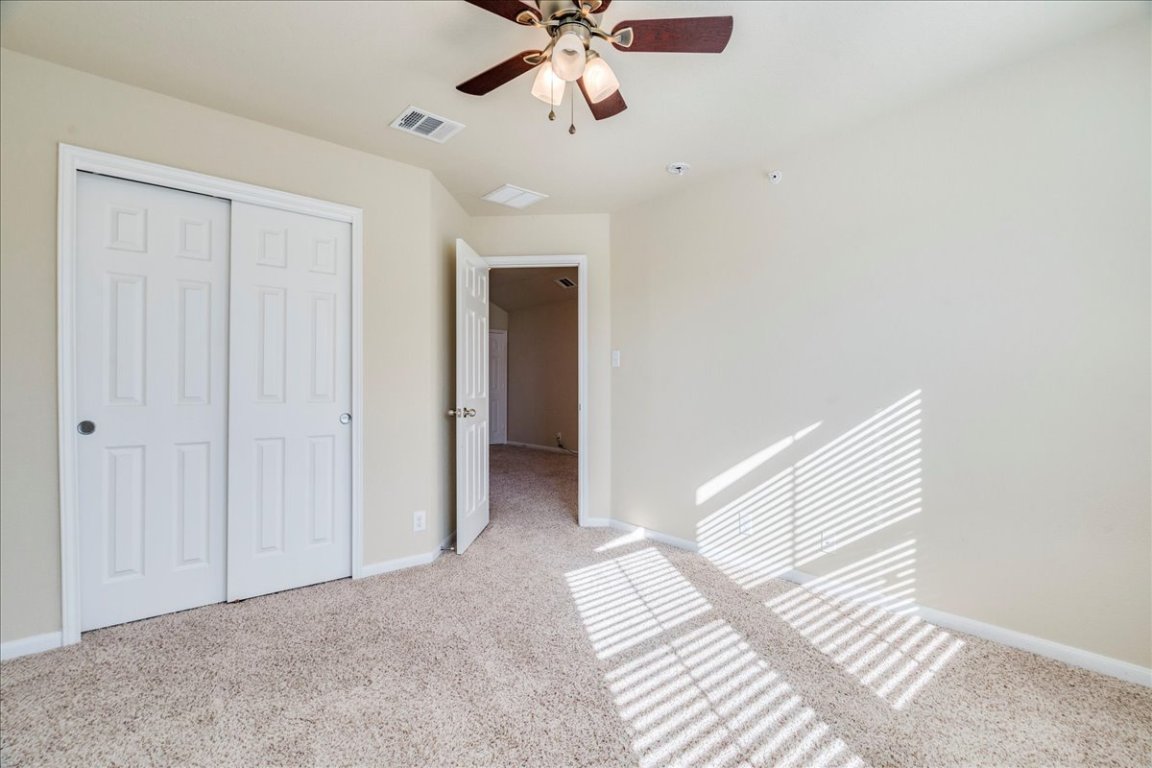 512 Lookout Tree Lane Round Rock, TX 78664 - Photo 23 of 29 Unfurnished bedroom featuring light carpet, ceiling fan, and a closet