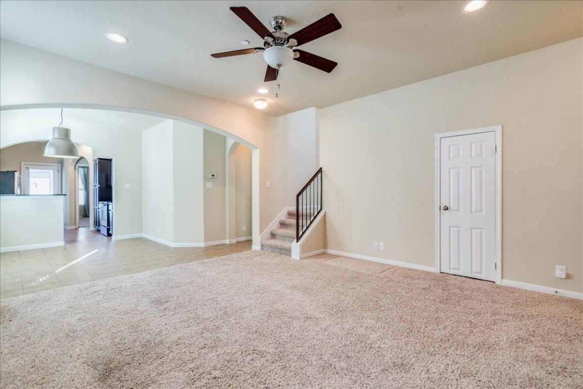 512 Lookout Tree Lane Round Rock, TX 78664 - Photo 7 of 29 Unfurnished living room with light carpet, stairs, a ceiling fan, arched walkways, and recessed lighting