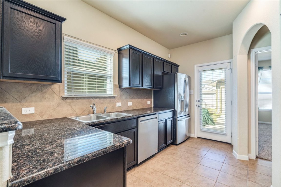 512 Lookout Tree Lane Round Rock, TX 78664 - Photo 9 of 29 Kitchen with healthy amount of natural light, decorative backsplash, dark stone countertops, and appliances with stainless steel finishes