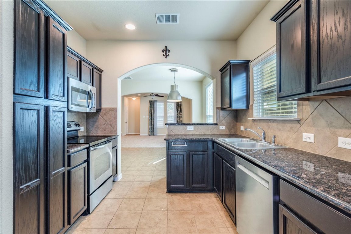 512 Lookout Tree Lane Round Rock, TX 78664 - Photo 10 of 29 Kitchen featuring appliances with stainless steel finishes, arched walkways, ceiling fan, pendant lighting, and backsplash