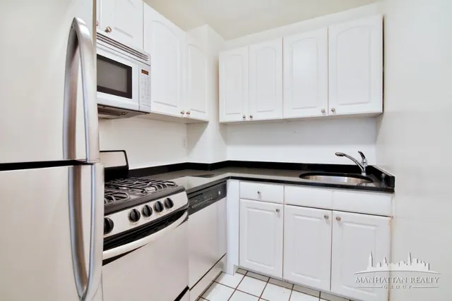 a kitchen with granite countertop white cabinets and stainless steel appliances