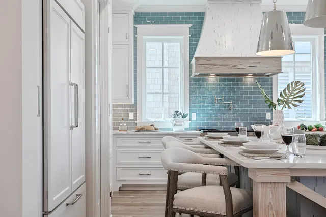 a large white kitchen with kitchen island a sink a stove a center island stainless steel appliances and a counter top space