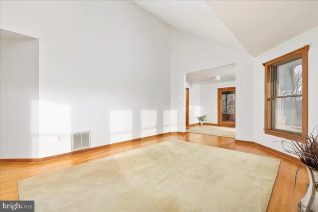 a view of an empty room with glass door and wooden floor