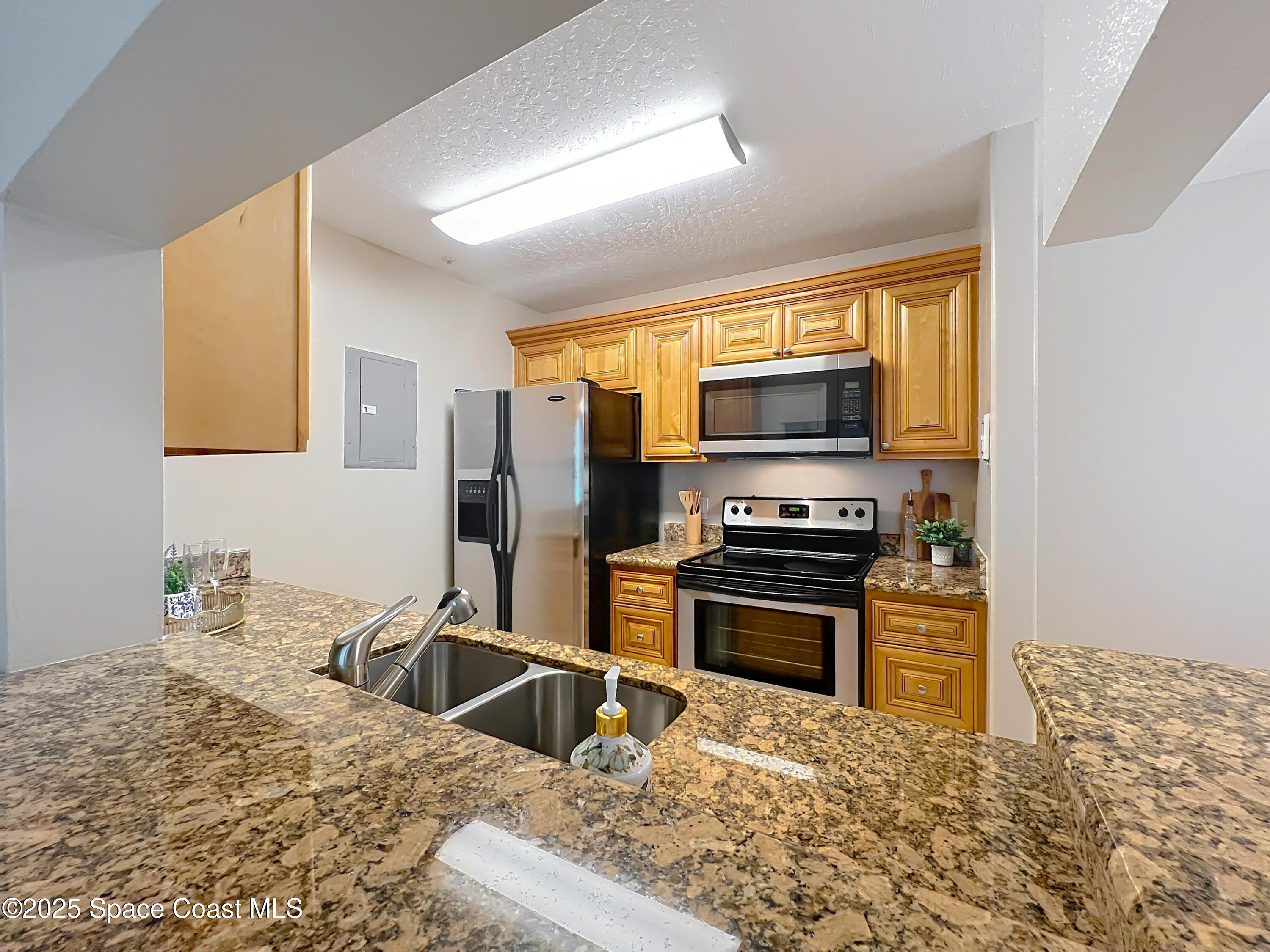 7667 North Wickham Road, Unit 410 Melbourne, FL 32940 - Photo 11 of 37 a kitchen with a stove a sink and a microwave
