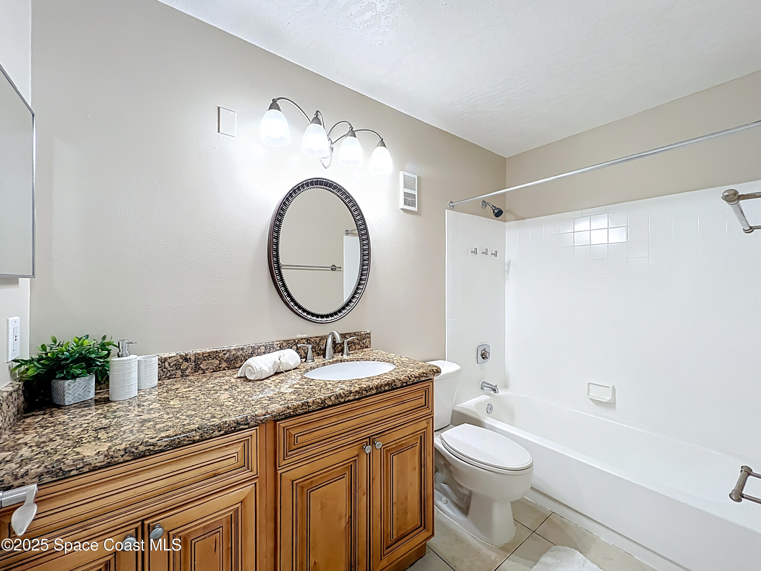 7667 North Wickham Road, Unit 410 Melbourne, FL 32940 - Photo 17 of 37 a bathroom with a granite countertop toilet a sink and a mirror