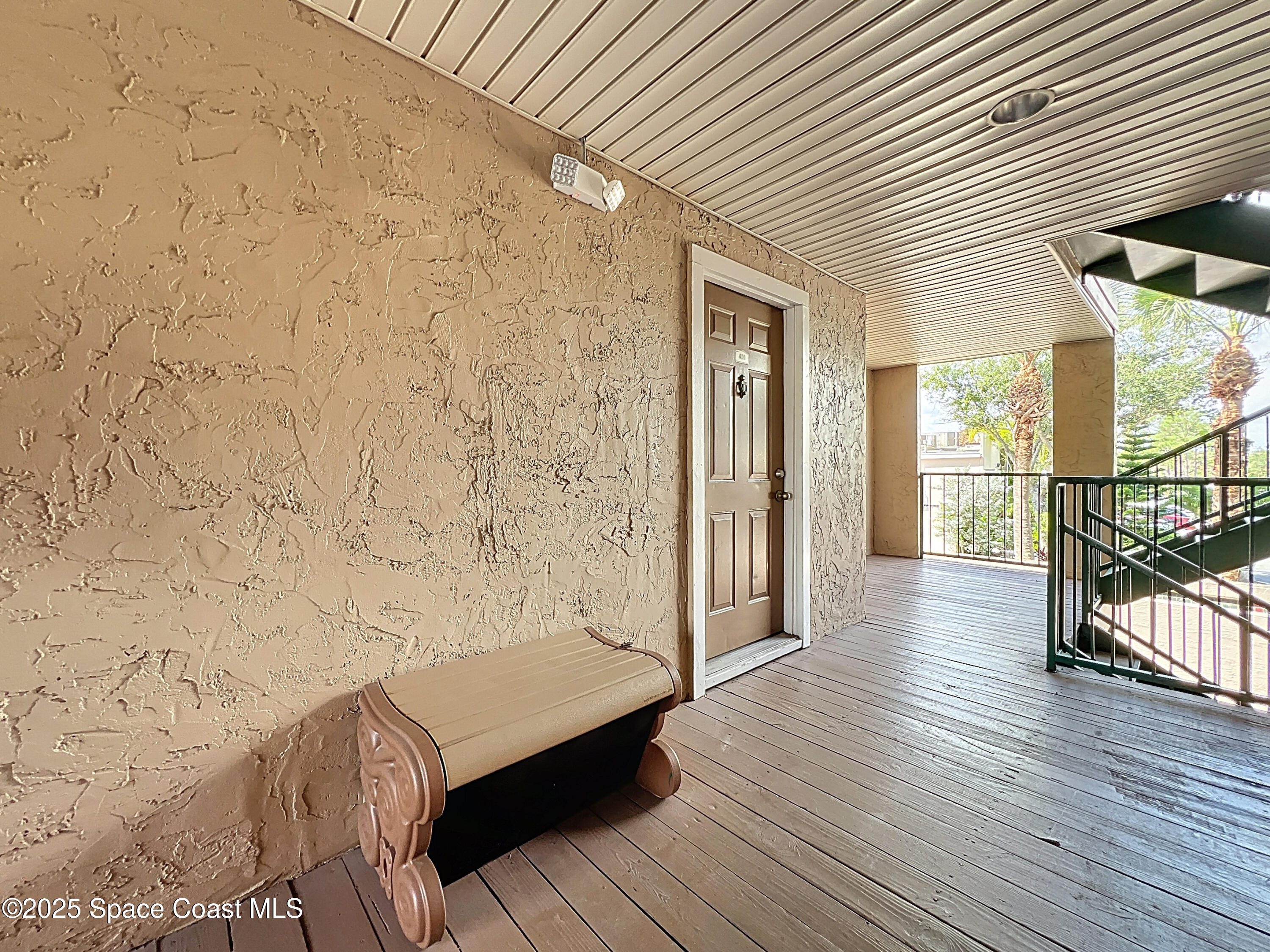 7667 North Wickham Road, Unit 410 Melbourne, FL 32940 - Photo 3 of 37 a view of a balcony with wooden floor and bench